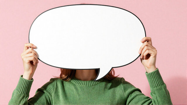 Woman holding blank white speech bubble in front of face for text or message concept