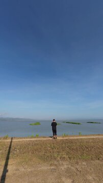 Man Standing by Water Under Clear Blue Sky