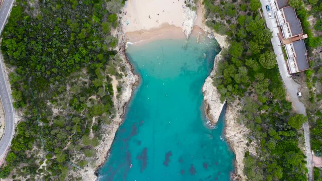 Aerial view of Cala Futadera, a secluded Mediterranean cove with crystal-clear turquoise waters, anchored boats, rugged cliffs and pine forests along the Costa Brava, Girona. 