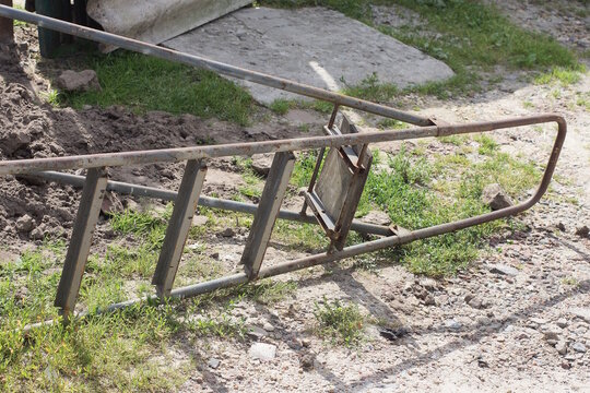 one gray aluminum ladder stepladder lies on the green grass and ground on the street