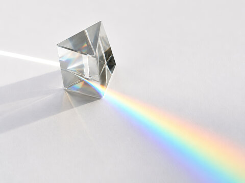 A single, transparent crystal cube reflects light in a vibrant rainbow of colors, creating a captivating geometric display of purity and refraction.