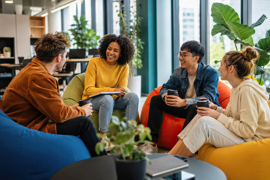 Four colleagues relax and converse around a modern office table, featuring beanbag chairs and a cityscape view.
