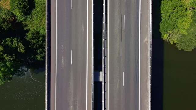 Top-down drone view of vehicles crossing a road bridge above the Mayenne River in France.