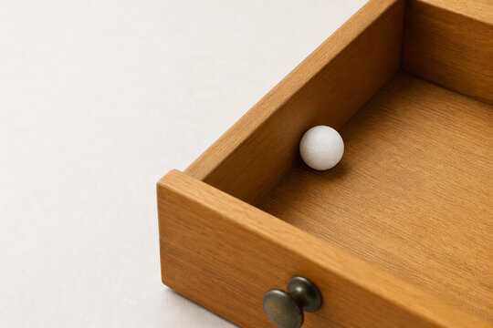 Single camphor ball in wooden drawer, household freshness and protection concept.