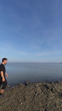 Man Walking by the Water Under a Clear Sky