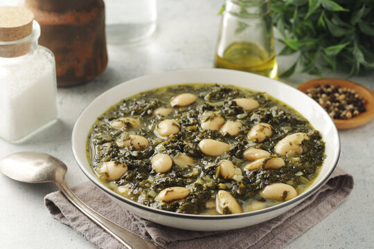 A bowl with traditional Tuscan kale salad and white beans soup Cavolo nero e fagioli