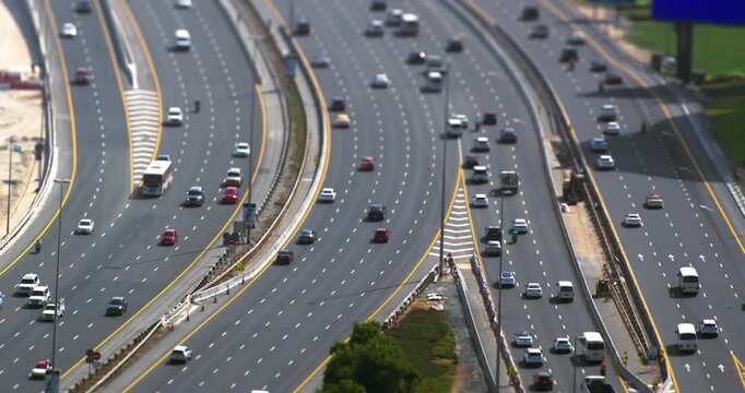 High angle view of busy highway traffic with cars and trucks driving on multi lane roads, using a tilt shift miniature effect