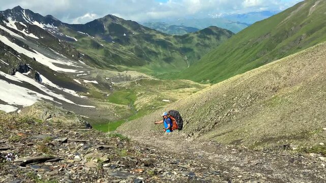 Climber ascending a rocky incline toward Chaukhi Pass carries expedition gear in Georgia, illustrating stamina training, personal achievement and physical performance under demanding alpine conditions