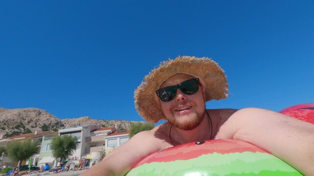 Man floating in turquoise sea near beach village