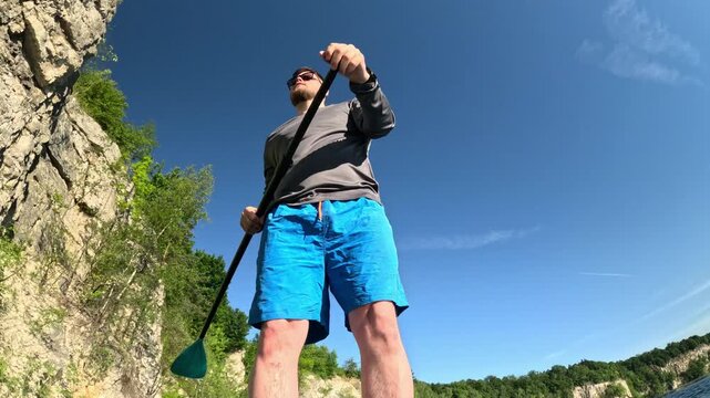 Man paddleboarding on rocky lake