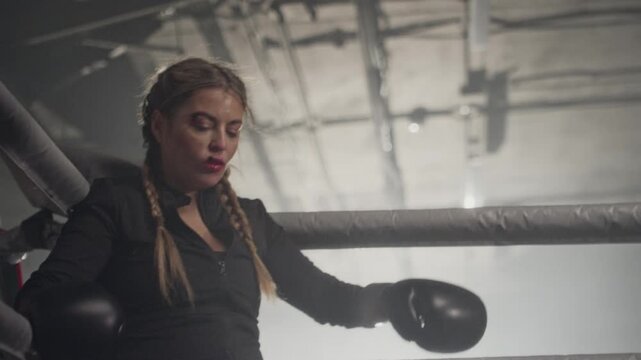 Caucasian young female boxer spitting out mouthguard after getting hit during sparring in slow motion. Footage is ideal for sports motivation and fitness brand commercials