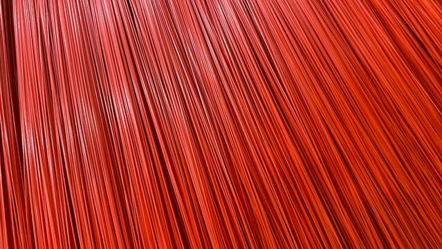 The texture of red synthetic broom bristles arranged closely to form a diagonal striped pattern. It showcases fiber details, bold color, and an abstract composition.