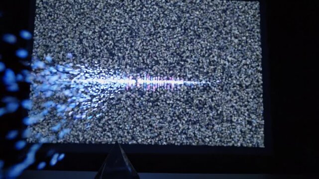Vibrant visual progression of colorful light waves and particles transforming into sound wave patterns on a digital screen in a darkened environment