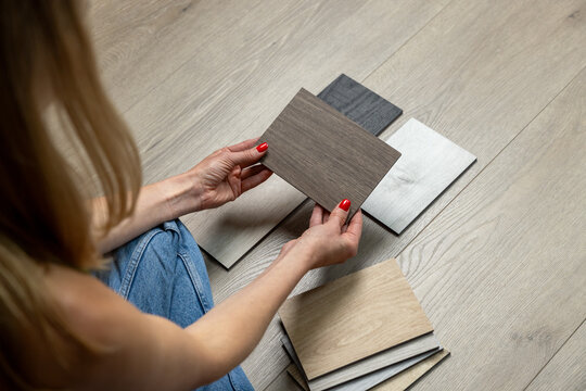 Woman sitting on floor and choosing wood flooring samples for home renovation and interior design