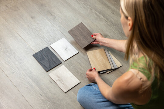 Woman sitting on floor and choosing wood flooring samples for home renovation and interior design