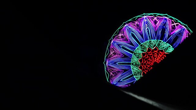 Mesmerizing spinning neon LED light pattern on giant wheel ride at night carnival