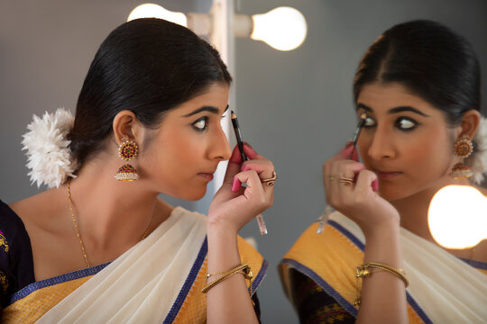 Classical dancer shading her eye brows in front of the mirror