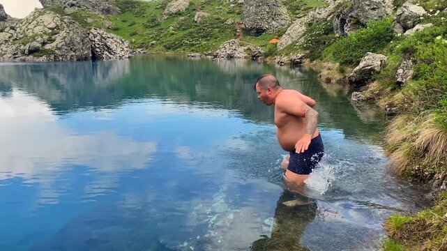 Tourist swimming in cold Blue Abudelauri Lake in Georgia experiences high-altitude open water among rocky Caucasus terrain, supporting adventure travel, trekking destinations and outdoor tourism