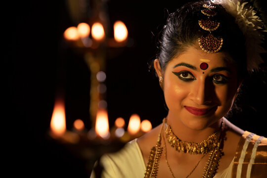 Mohiniattam dancer looking at a lamp with a smile