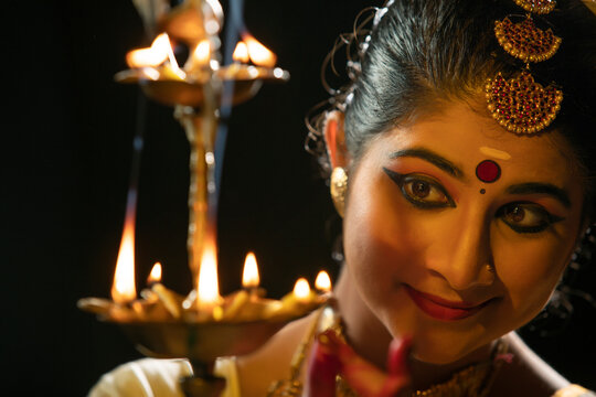 Mohiniattam dancer lighting a lamp with a smile