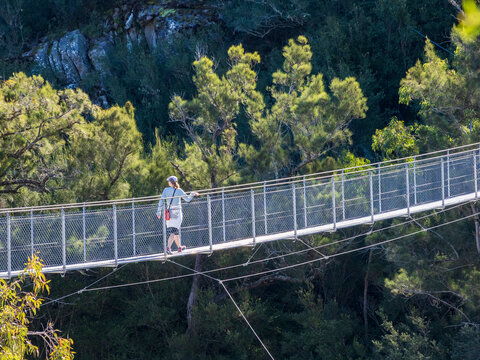 Hiker crossing suspension footbridge in landscape