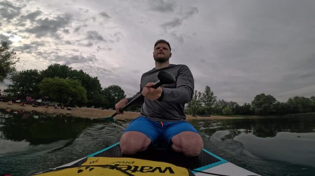 Man paddling SUP on cloudy lake