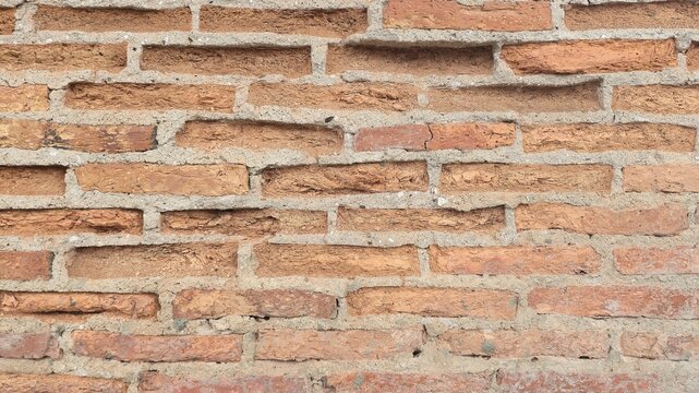 Antique red brick wall weathered vintage texture background. Front view of an old decaying orange brickwork structure with rugged mortar joints and realistic erosion.