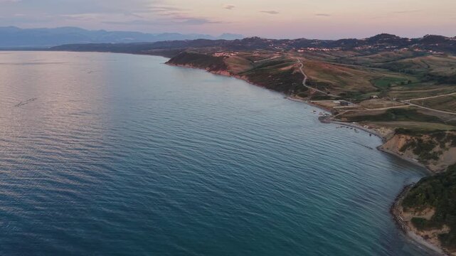 Wide drone view of a quiet beach, forested hills and clear Adriatic Sea along the coast of Kepi i Rodonit, Albania.

