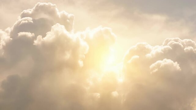 Bright sun shining through fluffy clouds in a soft golden sky at sunrise or sunset
