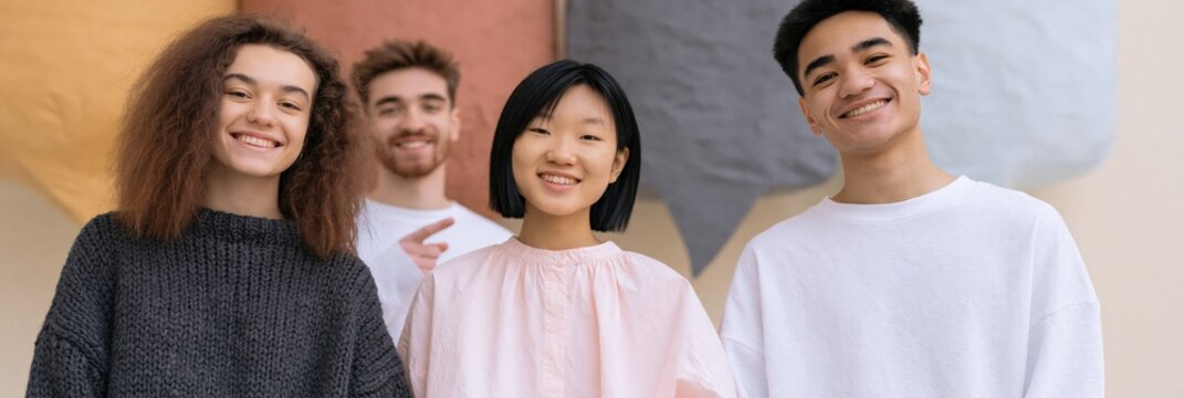 Group of diverse young friends smiling together against a textured wall for social media banner and youth lifestyle community background