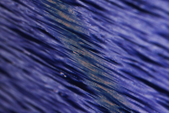 Macro view of a blue pixelated screen display revealing RGB subpixel structure and diagonal lines, creating an abstract textured pattern ideal for technology, background, and digital art concepts