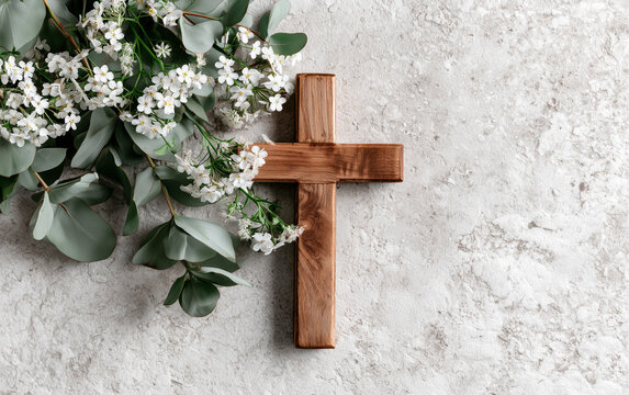 Rustic Wooden Cross Adorned with Delicate White Flowers and Green Eucalyptus Leaves on Textured Background