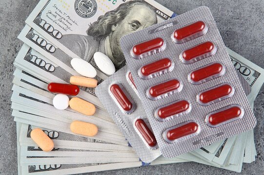 Pills and capsules on the background of a hundred dollar bill.t