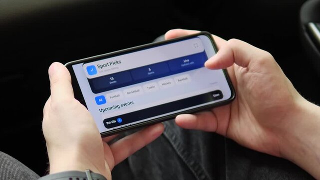 Hands hold a horizontal phone while browsing match markets and live odds, capturing the shift from traditional bookmakers to mobile gambling platforms.