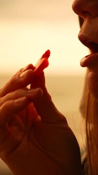 Sunset eating beach woman eats a red slice of fruit or snack on a beach during golden hour