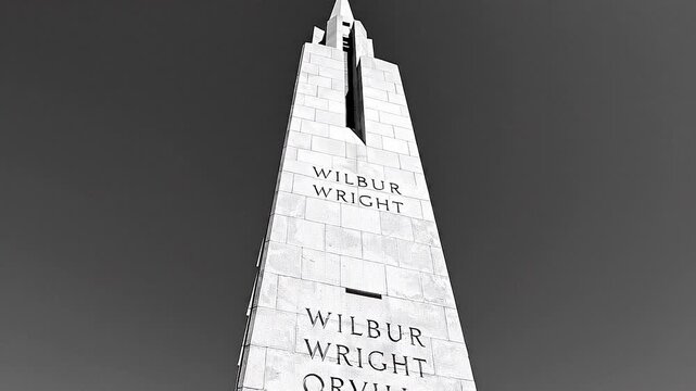 Bottom up tilt view of wright brothers national memorial monument under clear blue sky day.