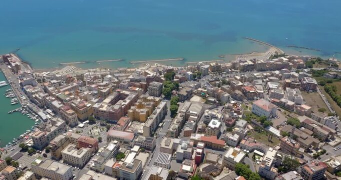 High aerial view of Anzio, a coastal town located near Rome, in Lazio, italy. There are urban buildings, historic central squares, and a scenic coastline along the vibrant blue Mediterranean sea.