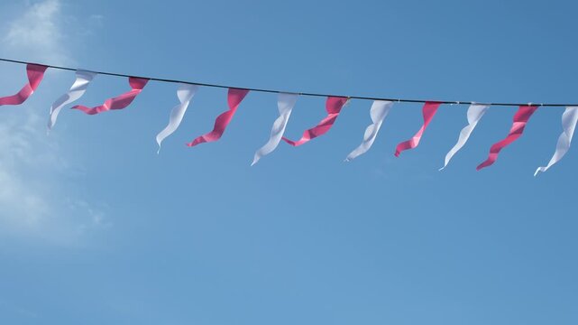 White and pink pennant bunting against a clear blue sky during golden hour. Swifts flying. Minimal. Copy space.