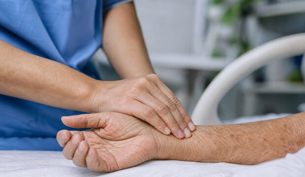 Nurse holding elderly patient hand in hospital. Supportive care for senior in palliative clinic. Medical professional providing compassion and comfort to aging citizen in recovery.