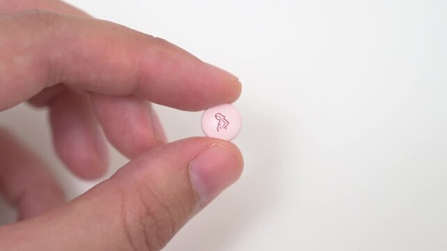 A hand holds and presents a pink maternal healthcare tablet with an approved pregnancy icon