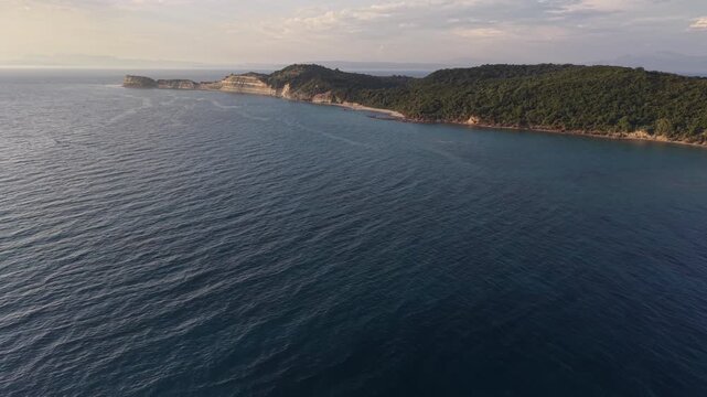 Wide drone view of a quiet beach, forested hills and clear Adriatic Sea along the coast of Kepi i Rodonit, Albania.
