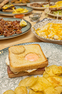 Toasted Egg Yolk Sandwich with Chips in Focus, Restaurant Table Spread Blurred in Background