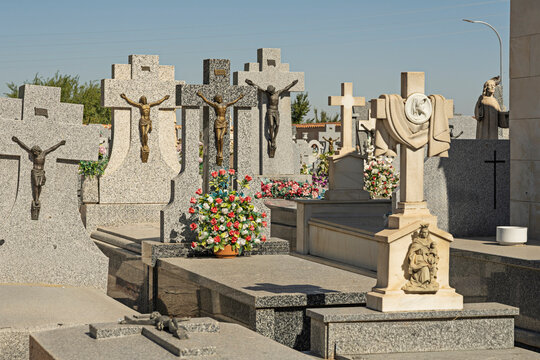 Close-Up of Granite Crucifix Headstones and Religious Statuary With Fresh Flower Tributes