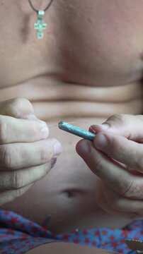 Angler preparing fishing gear by threading line through a lead weight in his lap. Extreme close-up shot.