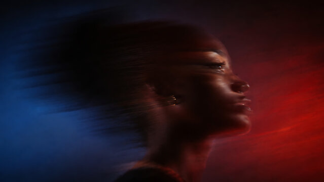 Dramatic portrait of a young woman with motion blur and vibrant red and blue lighting