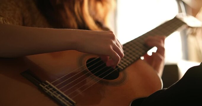 Cinematic close-up of hands playing a classical acoustic guitar in warm natural light with shallow depth of field, representing music, creativity, learning, and artistic expression.

