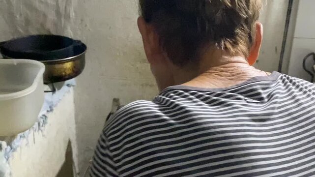 A Latina woman cooks delicious corn arepas in a pan on a stove inside a home in Neiva, Huila, Colombia. Concept of Colombian food and gastronomy