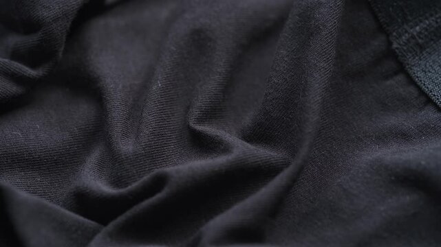 A close-up texture of soft wrinkled black jersey fabric.