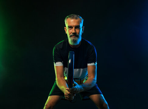Old man. Padel tennis player with racket. Man athlete with paddle racket on court with neon colors. Sport concept. Download a high quality photo for the design of a sports app or betting site.