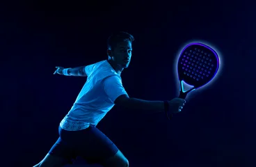 Padel tennis player with racket. Man athlete with paddle racket on court with neon colors. Sport concept. Download a high quality photo for the design of a sports app or betting site. © Mike Orlov